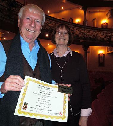 A couple holding a certificate and seat plaque